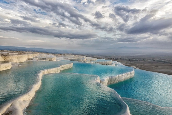 Pamukkale, Denizli, Thổ Nhĩ Kỳ: Pamukkale dịch ra có nghĩa là “lâu đài bông”. Tên gọi này xuất phát từ màu trắng huyền ảo của những bờ đá hình thành do suối nước nóng ở miền Tây Nam Thổ Nhĩ Kỳ. Được coi là báu vật quốc gia, nơi này được bảo vệ chặt chẽ, nhưng du khách vẫn được phép xuống ngâm mình trong những hồ nước nhỏ và nông này. Ảnh: Ibellhop.